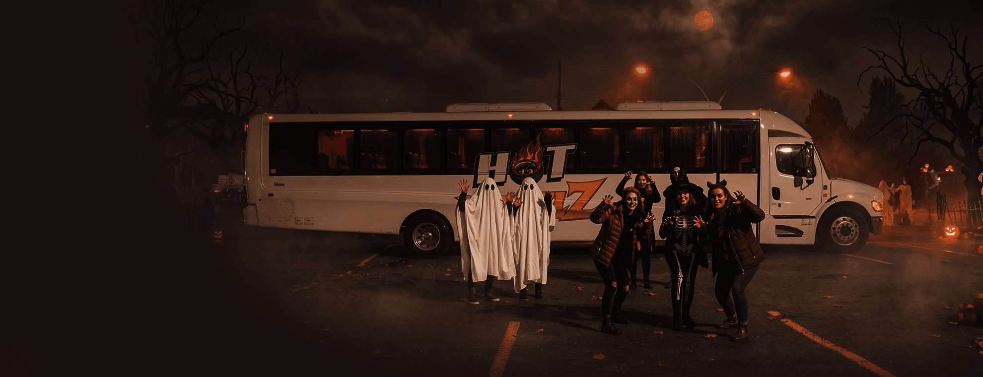 Friends in Halloween costumes outside a Hotwheelz party bus